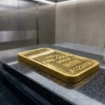 Lingotin d'or de 100 grammes posé sur une surface en granit poli dans un environnement sécurisé, idéal pour un premier achat d'or physique