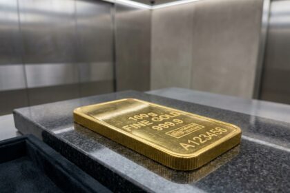 Lingotin d'or de 100 grammes posé sur une surface en granit poli dans un environnement sécurisé, idéal pour un premier achat d'or physique